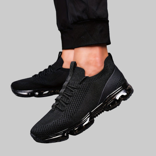 Black Women's Flying Woven Running Shoes worn with black pants on a wooden floor.