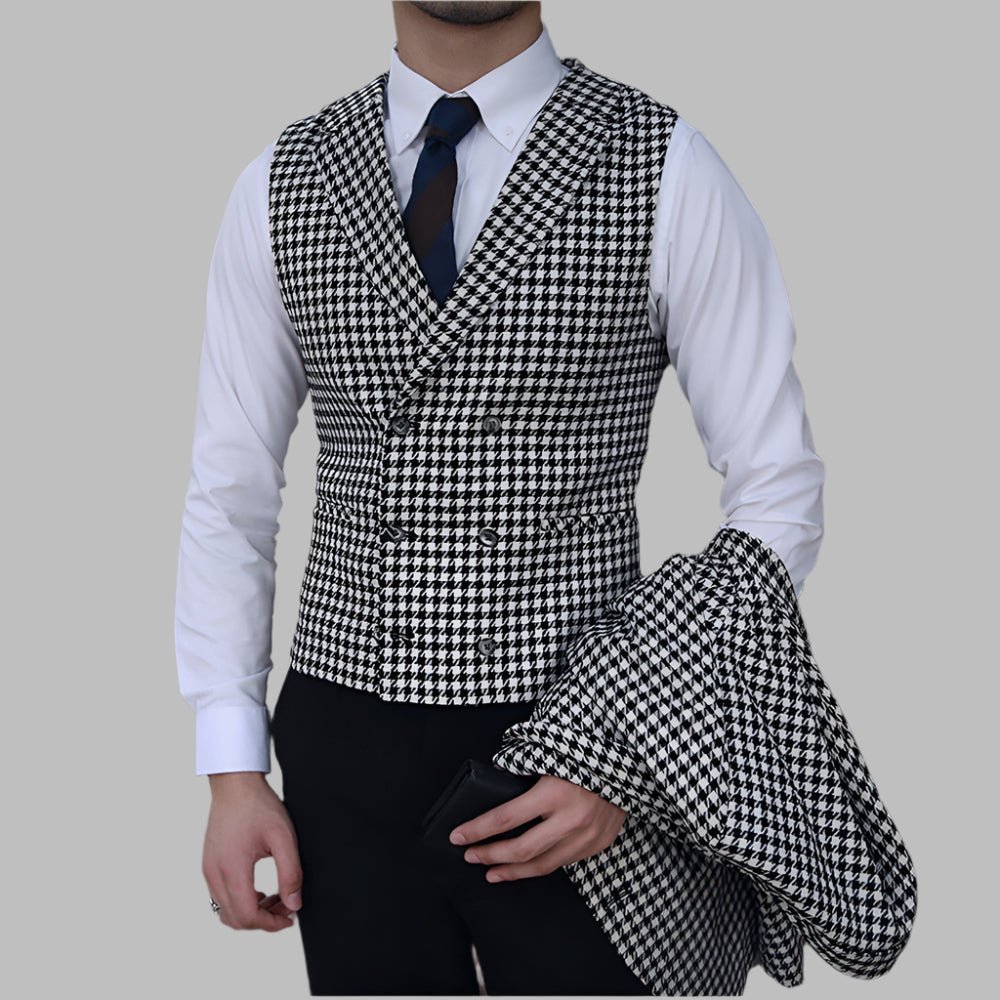 Man wearing a houndstooth patterned vest over a white shirt with a blue tie on a gray background