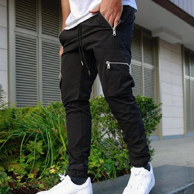Person wearing black cargo jogger pants with white sneakers in front of a building.