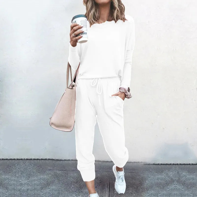 Person wearing a white outfit holding a coffee cup against a plain background