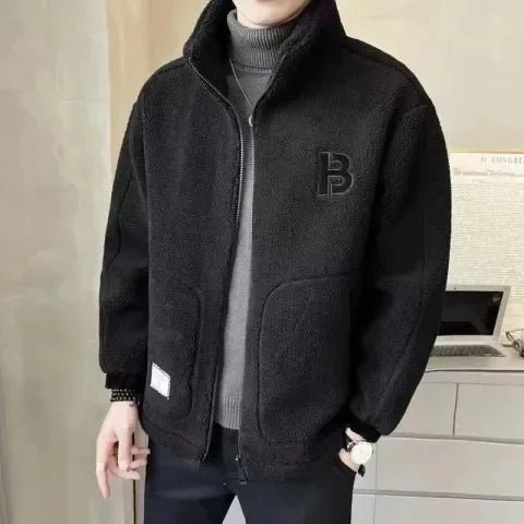 Person wearing a black fleece jacket with a logo in an indoor setting