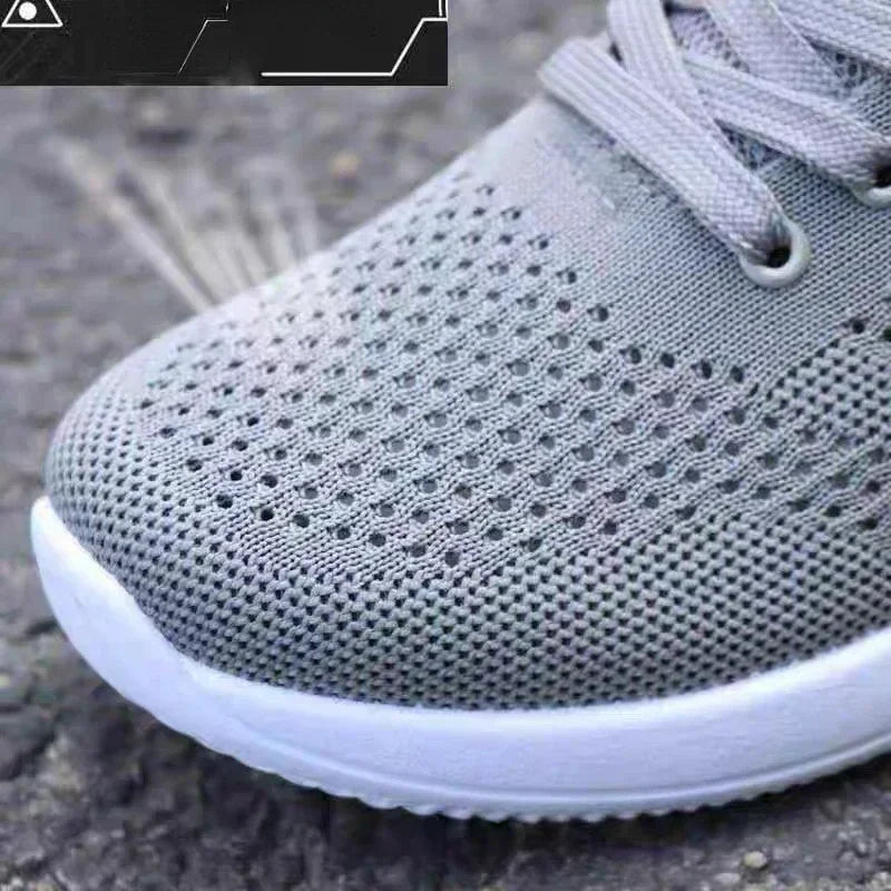 Gray sneaker with white sole on a textured surface