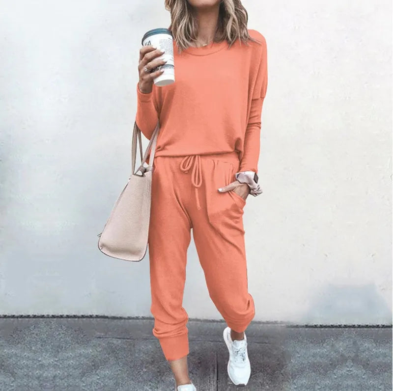 Woman wearing a peach tracksuit holding a coffee cup against a plain background