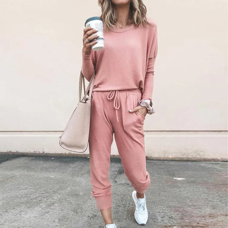 Person wearing a pink tracksuit holding a coffee cup against a plain background